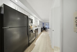 Eine moderne Küche mit einem schwarzen Kühlschrank, Edelstahlgeräten und weißen Schränken.