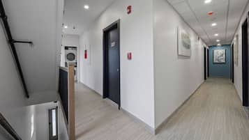 A hotel corridor with a staircase, a door labeled '207', and a laundry room in the background.