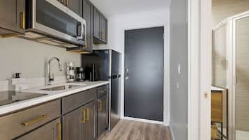 Una cocina moderna con electrodomésticos de acero inoxidable, microondas integrado y una puerta oscura.