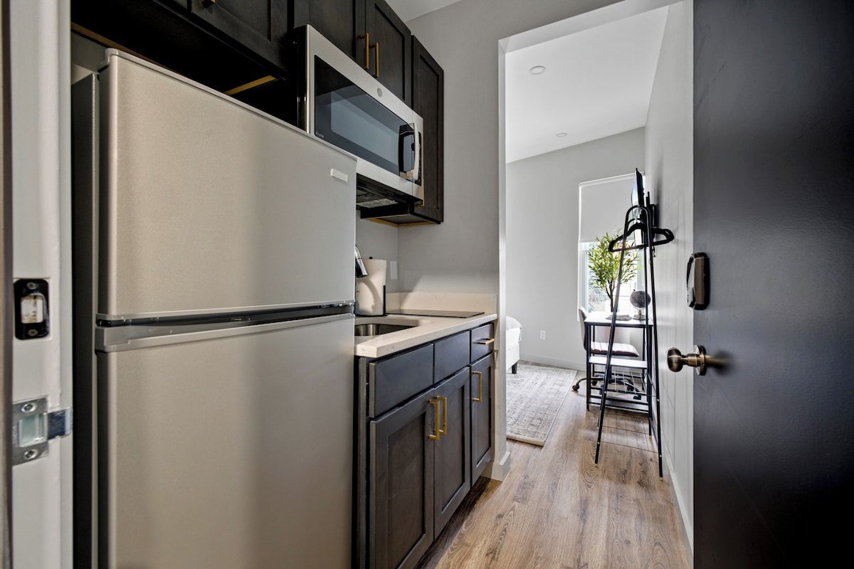 A kitchen with a refrigerator, microwave, and dark cabinets.