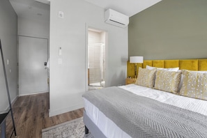 Een hotelkamer met een bed, nachtkastje, lamp en airconditioning.