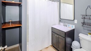 Une salle de bain avec un rideau de douche, un lavabo, des toilettes et un miroir.