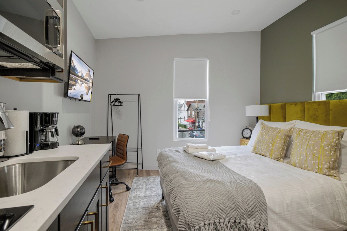 Een moderne slaapkamer met een bed, een bureau, een stoel, een raam en uitzicht op het omliggende landschap.