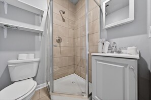 Ein Badezimmer mit Duschkabine, Toilette und Waschbecken mit Spiegel darüber.