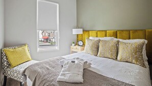 Ein Hotelzimmer mit Bett, Nachttisch, Lampe, Fenster und Blick nach draußen.
