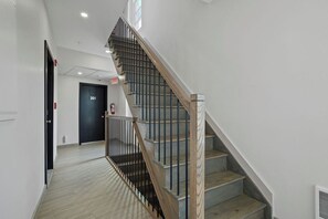 A staircase with a wooden handrail and metal balusters, leading to a door marked '201'.