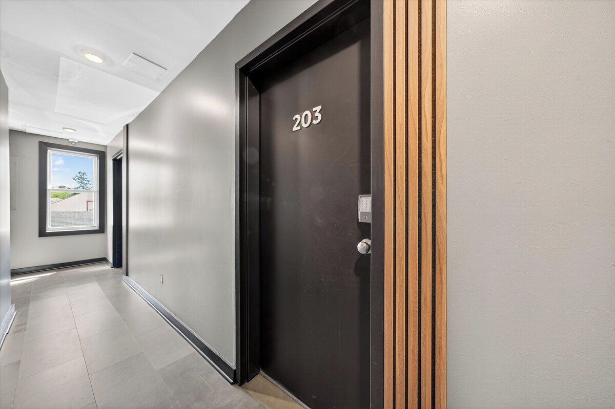 A hallway with a black door marked '203' and a window with a view of greenery.