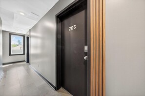 Un pasillo con una puerta negra marcada '203' y una ventana con vistas a zonas verdes.