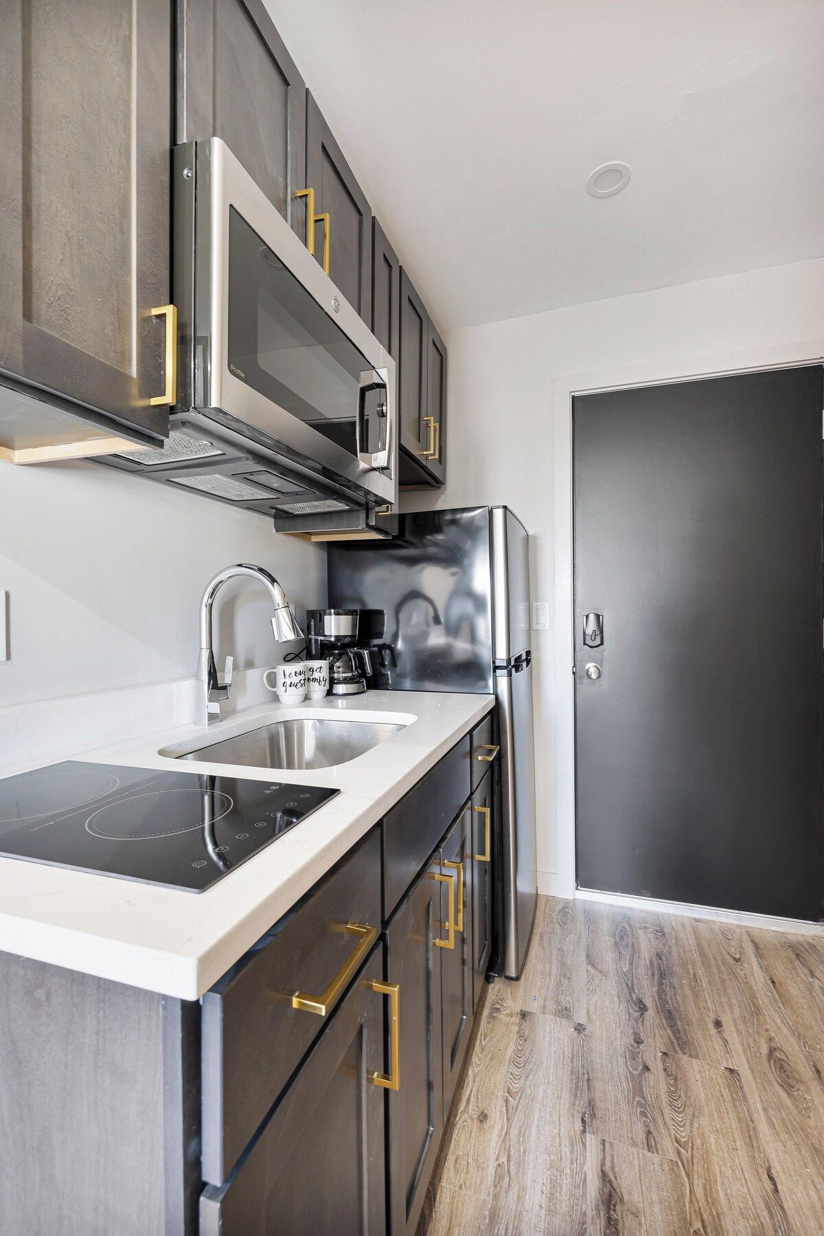 A modern kitchen with a built-in microwave, stainless steel appliances, and a black refrigerator.
