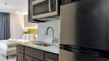 A modern kitchen with dark cabinetry, a stainless steel refrigerator, and a built-in microwave.
