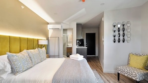 Una camera d'albergo con un letto grande, un'area salotto, una cucina e un bagno.