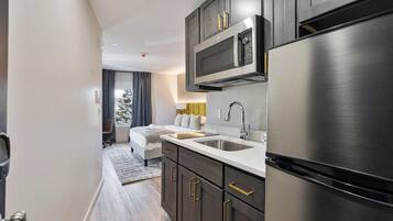 A modern kitchen with dark cabinetry, stainless steel appliances, and a white countertop.