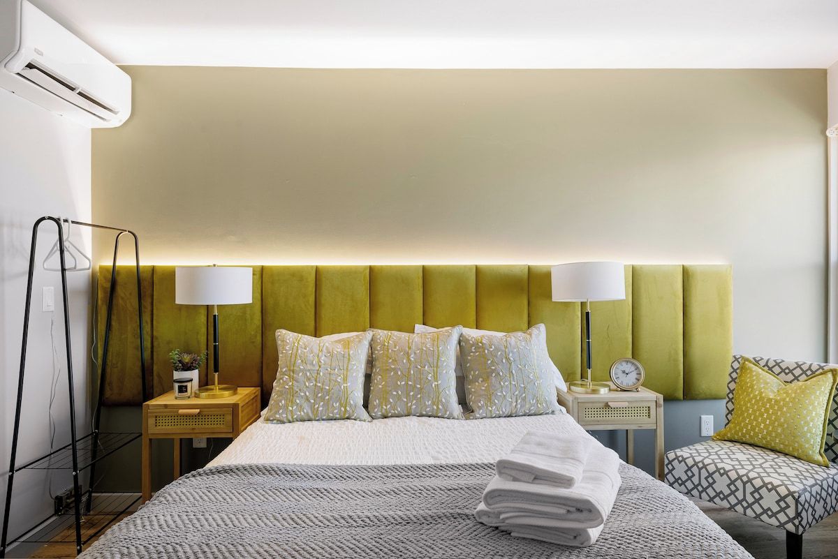 A hotel room with a bed, bedside tables, lamps, and a chair.