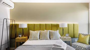 A hotel room with a bed, bedside tables, lamps, and a chair.