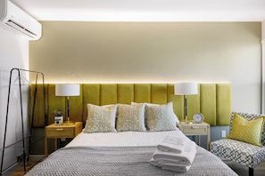 Ett hotellrum med en säng, sängbord, lampor och en stol.