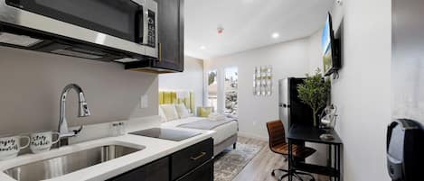 A modern kitchen with a stainless steel range hood, a double sink, and a dining area with a table and chairs.