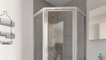 Une salle de bain moderne avec une douche à parois de verre, des toilettes, un lavabo avec un miroir et un porte-serviettes fixé au mur.