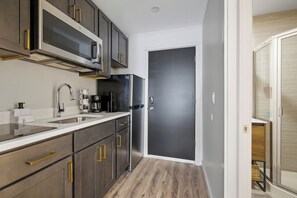Cozinha moderna com eletrodomésticos de aço inoxidável, armários de madeira e porta escura.