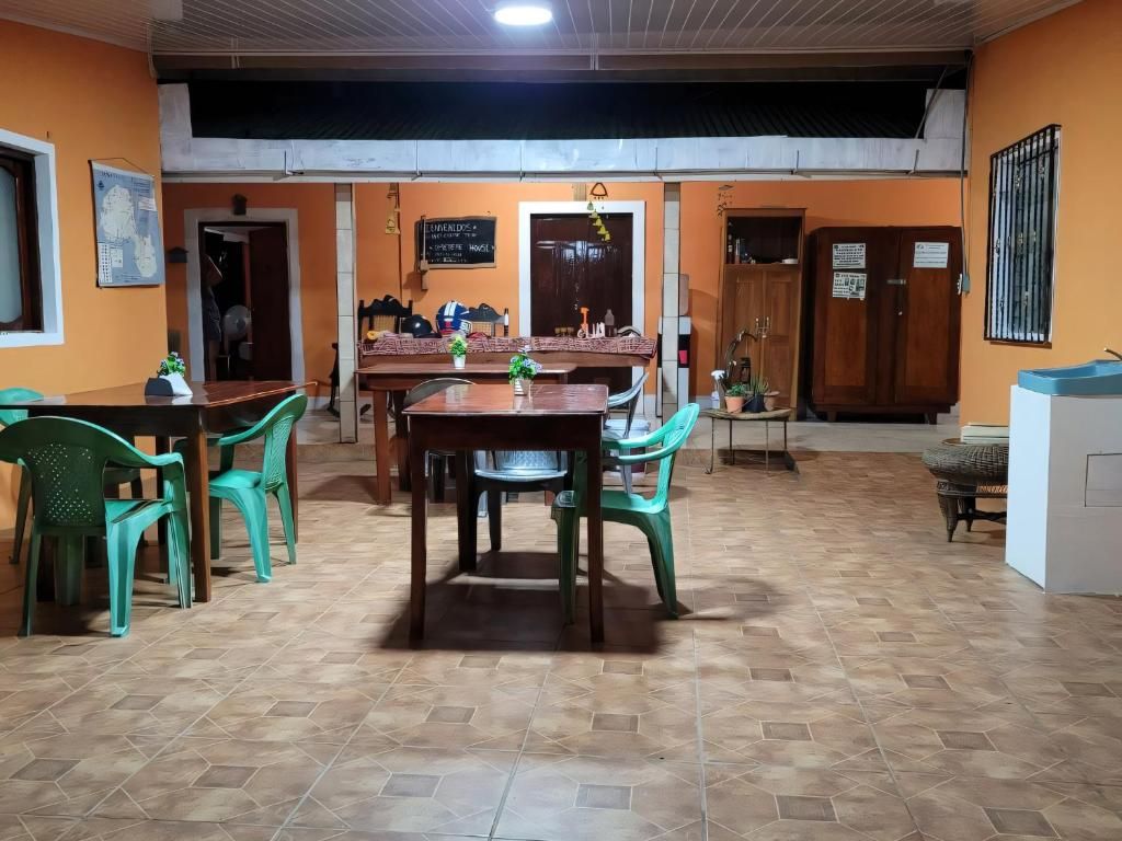 Un espace repas avec une table et des chaises en bois, un sol carrelé et un panneau fixé au mur.
