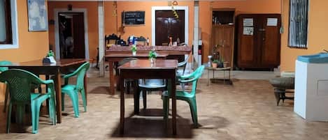 A dining area with a wooden table and chairs, a kitchen area with cabinets, and a tiled floor.
