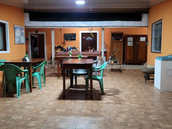 Un espace repas avec une table et des chaises en bois, un coin cuisine avec des placards et un sol carrelé.