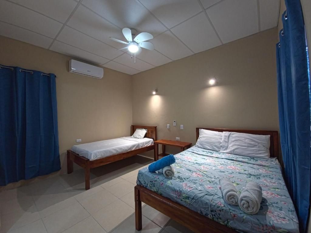 Una habitación con dos camas individuales, ventilador de techo, aire acondicionado y una pequeña mesa.