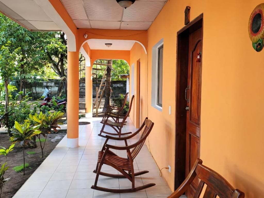 An outdoor patio area with a wooden bench, a door, and a view of a garden.