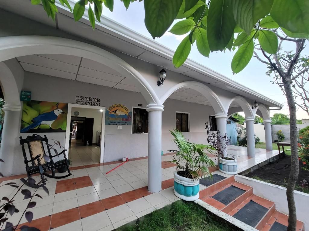 Área externa coberta com piso de azulejos, plantas em vasos e um banco.