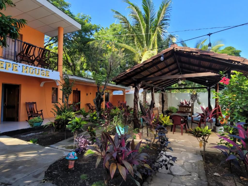 Une maison avec une enseigne indiquant « EPE HOUSE » et un espace extérieur abrité avec des chaises et des tables.