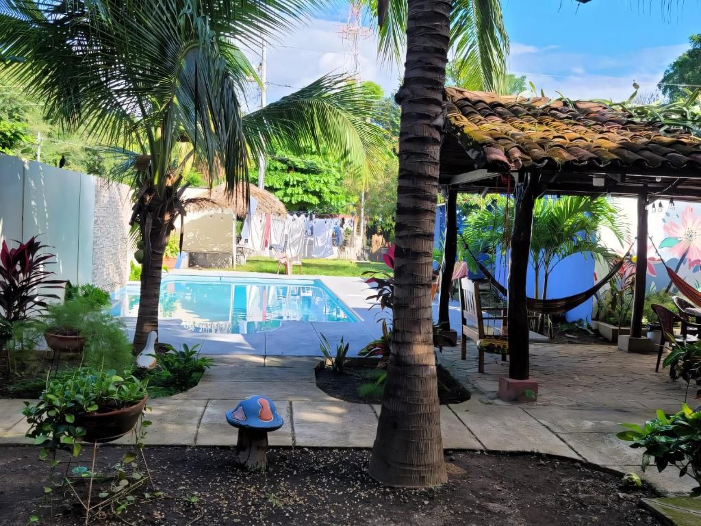 Un área de piscina con un pabellón, palmeras y una hamaca.