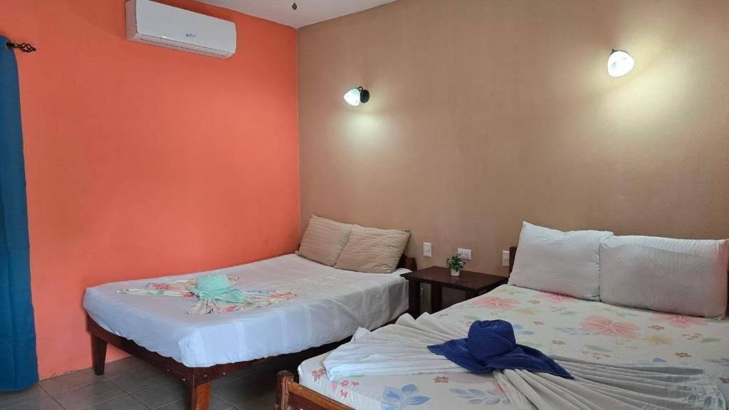 Une chambre avec deux lits, une petite table et un climatiseur fixé au mur.