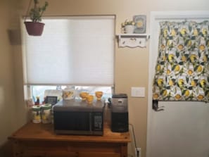 Une cuisine équipée d’un four à micro-ondes, d’une machine à café et d’une plante en pot.