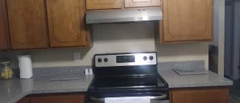 A kitchen with wooden cabinets, a stainless steel oven, and a granite countertop.