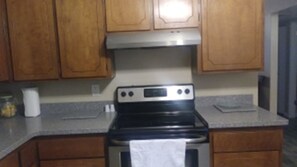 Une cuisine avec des meubles en bois, une cuisinière en acier inoxydable et un plan de travail en granit.