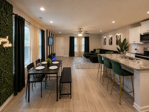 A modern kitchen with a bar area, a dining table with chairs, and a living area with a sofa. - Houston Family-Friendly Retreat Stylish 3BR Stay for Groups & Getaways (Houston)