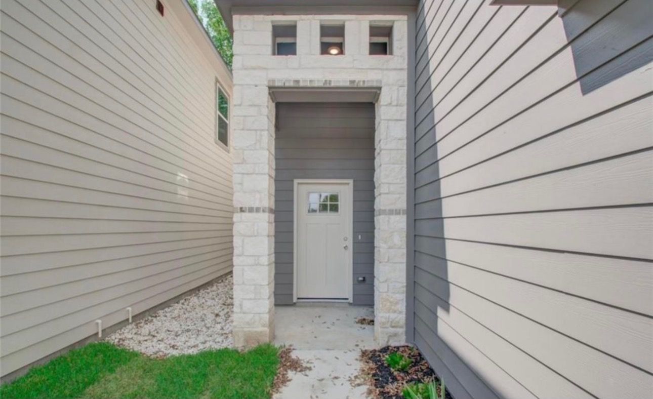 A residential building with a central door, flanked by two side walls, and a small overhang above the door.