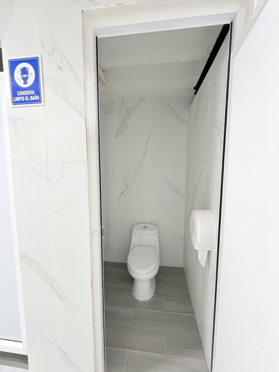 A narrow bathroom with a toilet, a hand dryer, and a sign instructing to keep the bathroom clean.