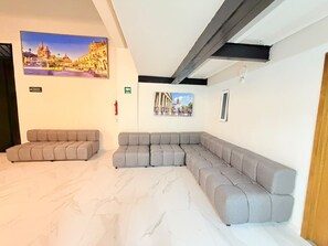 Una sala de estar moderna con un sofá modular, un televisor de pantalla plana montado en la pared y piso de mármol.