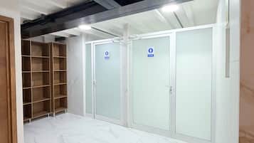 Un pasillo con piso de mármol, un estante de madera y dos puertas de vidrio con un letrero azul.