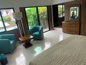 A hotel room with a large bed, two armchairs, a small table, a dresser, and a mirror. - 5 bedrooms | Heated pool | Movie theater | Pool table - CASA ISELA (Cuernavaca)