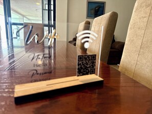 A wooden table with a QR code and a Wi-Fi symbol, a framed picture on the wall, and a couch in the background. - 5 bedrooms | Heated pool | Movie theater | Pool table - CASA ISELA (Cuernavaca)