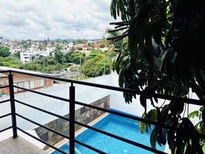A balcony with a pool, overlooking a cityscape with buildings and greenery. - 5 bedrooms | Heated pool | Movie theater | Pool table - CASA ISELA (Cuernavaca)