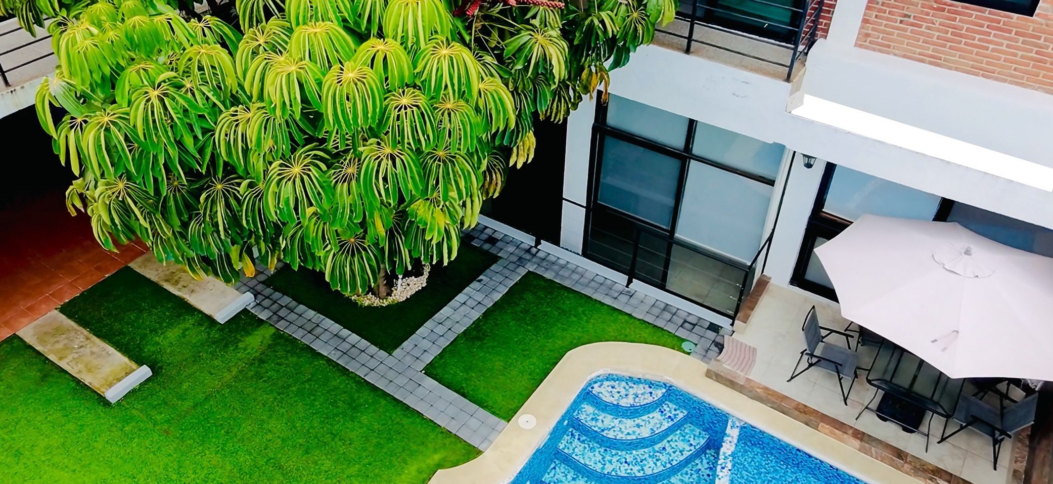 A rooftop garden with a swimming pool, a seating area, and a large tree.