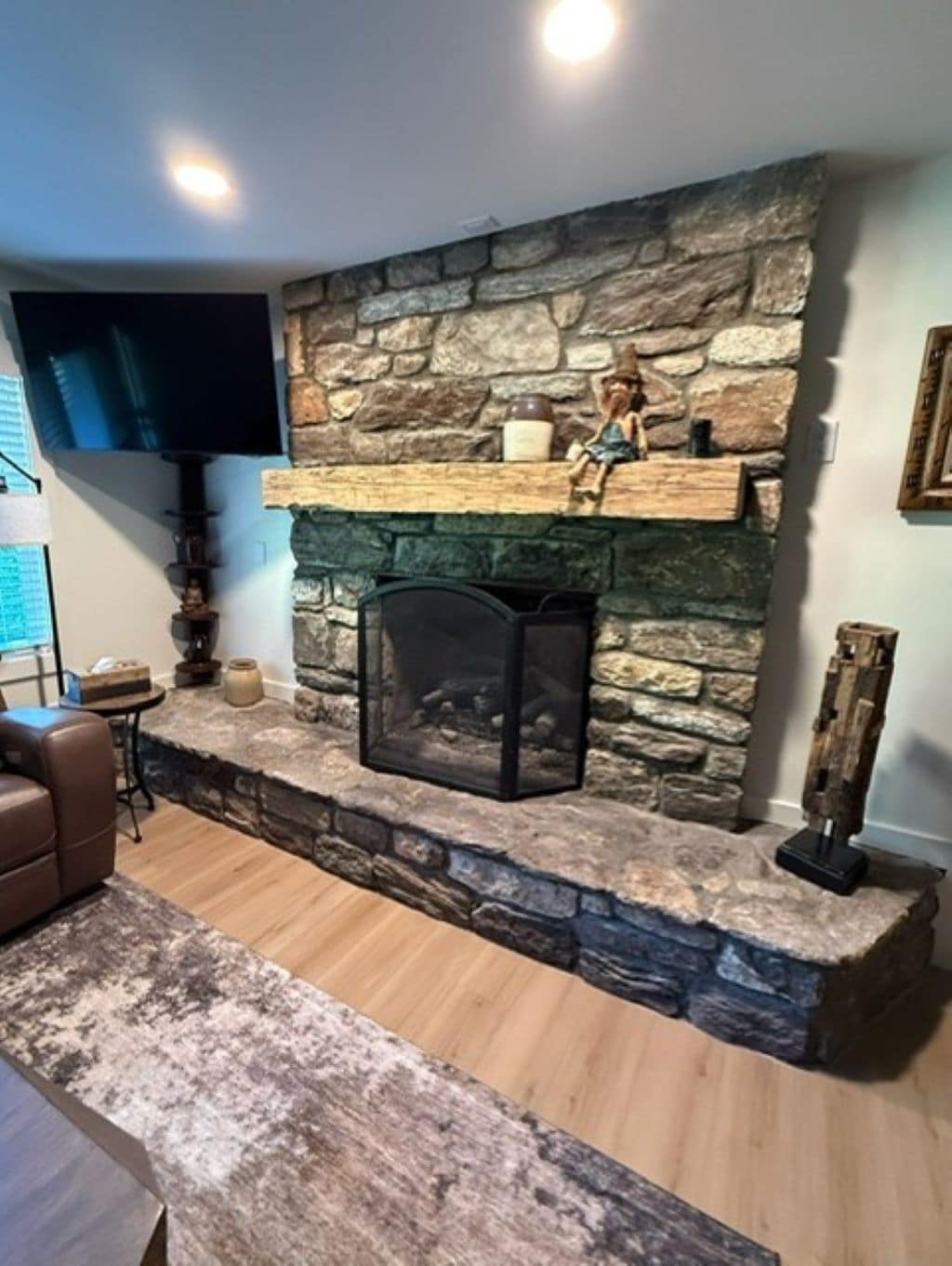A stone fireplace with a television mounted above it, a leather sofa, and a wooden coffee table.