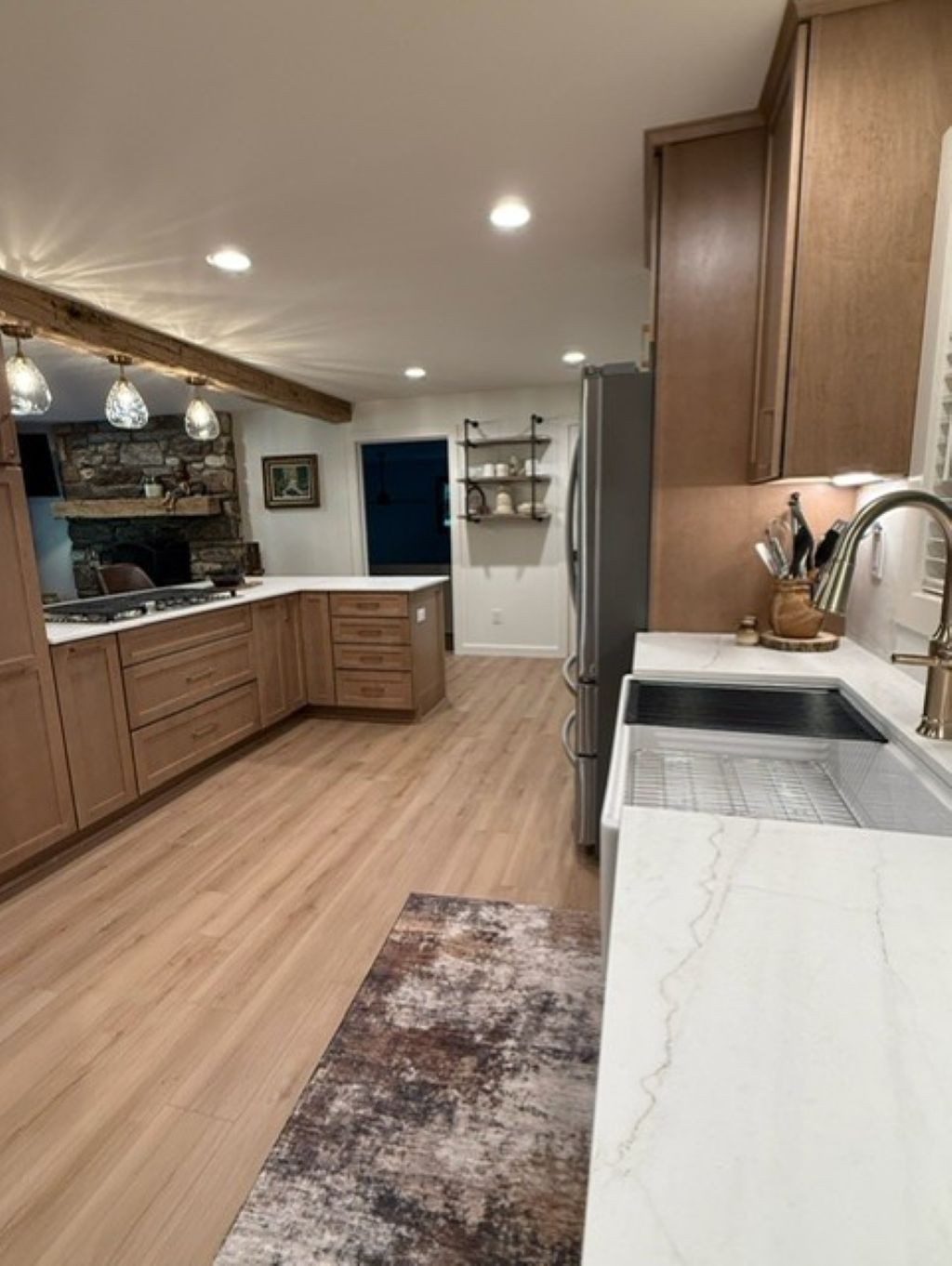 A modern kitchen with wooden cabinets, a marble countertop, and a built-in oven.