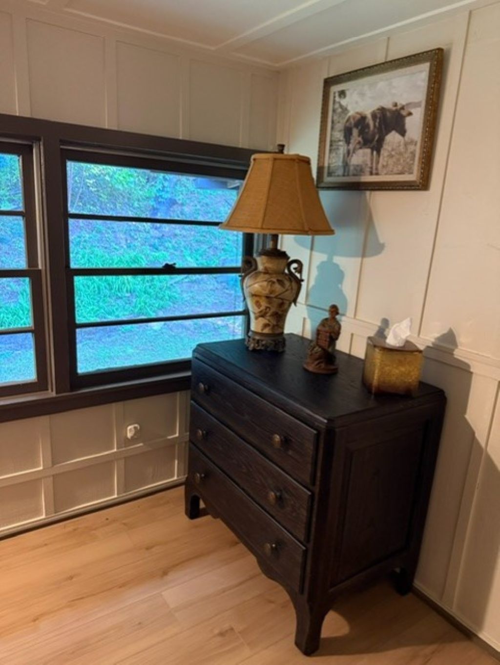 A dark wooden dresser with drawers, a vase, and a lamp on top.