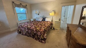 A bedroom with a bed, bedside lamps, a dresser, and a window with curtains.