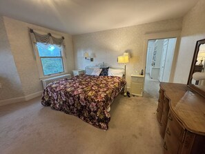 A bedroom with a bed, bedside lamps, a dresser, and a window with curtains.