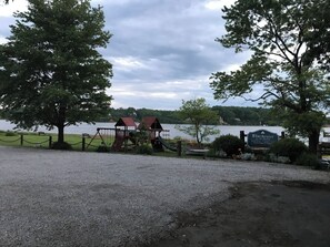 A playground with swings and a slide, a sign reading 'Winchester,' and a body of water in the background.
