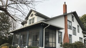 A two-story house with a large front porch, a chimney, and a covered front entrance.